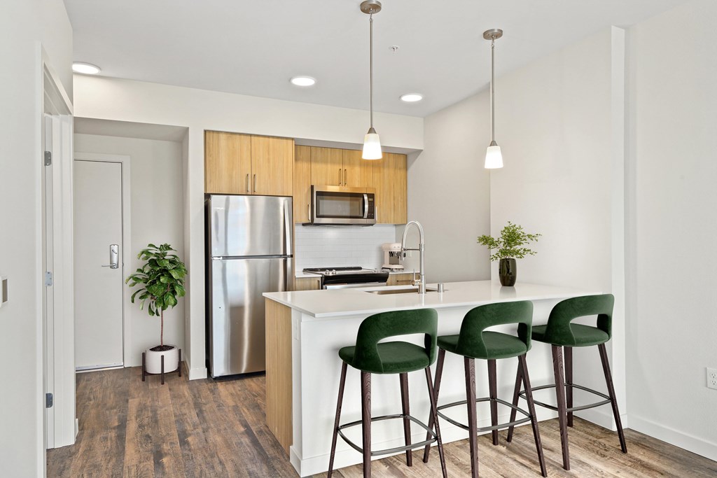 A kitchen with a white counter and green bar stools.